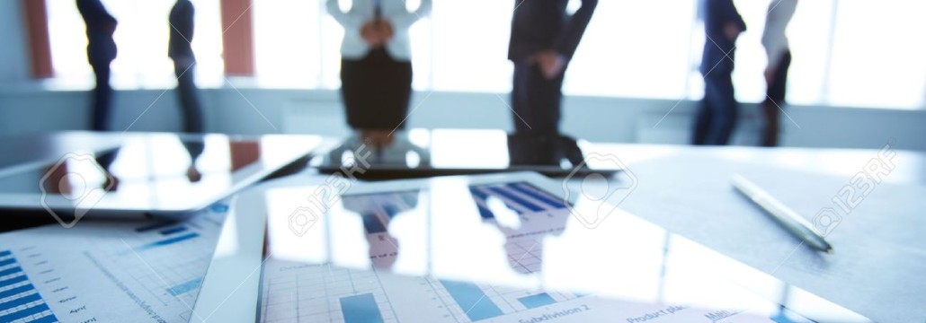 23406729-Close-up-of-business-document-in-touchpad-at-workplace-on-background-of-office-workers-interacting-Stock-Photo